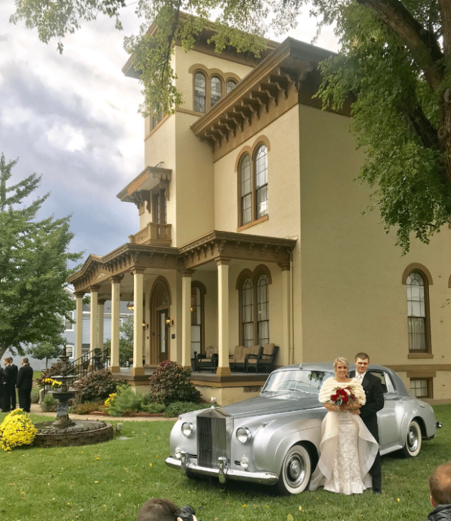 Happy couple standing in front of The Pepin Mansion next to a vintage Rolls Royce