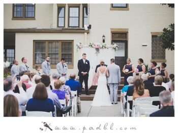 Wedding ceremony taking place outdoors with guests seated and the couple standing together in front of a historic building