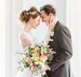 Bride and Groom smiling at each other with their heads touching, holding flowers