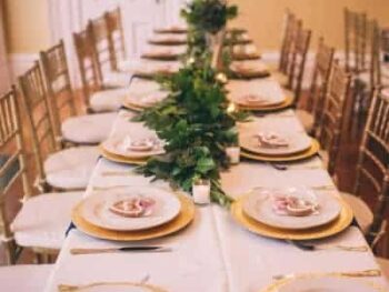 Large table with plates, forks, knives, and flowers for Rehearsal Dinners