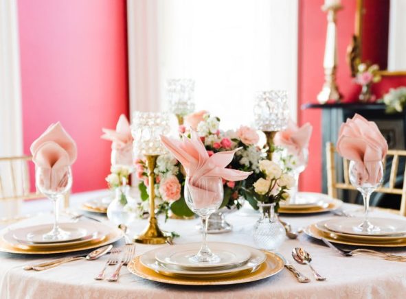 Table set with plates, silverware, wine glasses, and pink napkins